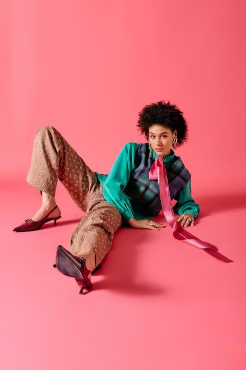Model in a colourful knit set on a pink background